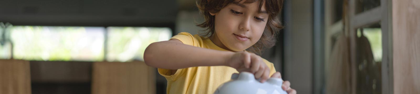 Little boy getting money out of his piggy bank